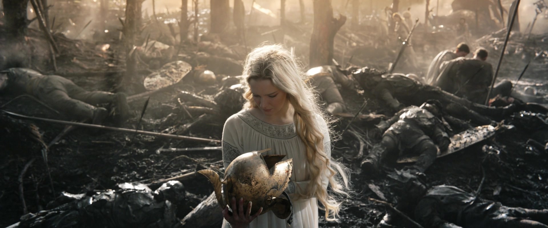 Galadriel helmet Galadriel in a white dress in the middle of a scene of devastation, burned trees and bodies, holding a helmet